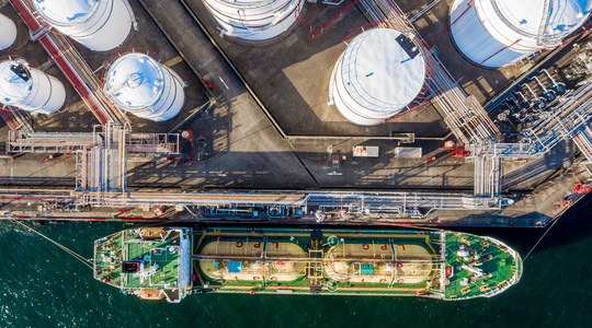 Dronefoto van tanker aangemeerd bij opslagtanks