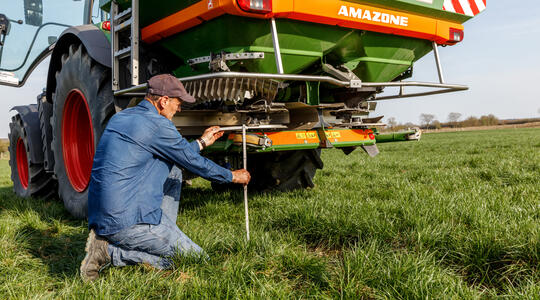 een boer stelt zijn kunstmeststrooier in