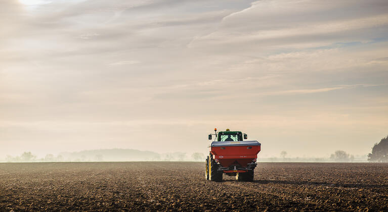 trekker met kunstmeststrooier op het land