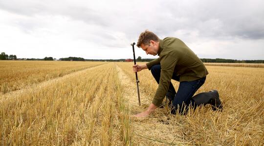 Un agriculteur analyse la terre de son champ