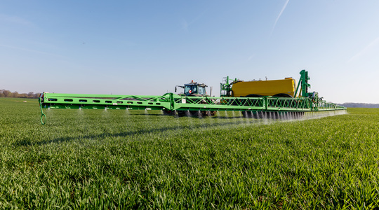 Tractor met veldspuit in tarwe