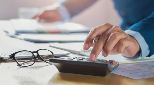Hand van man die werkt op calculator